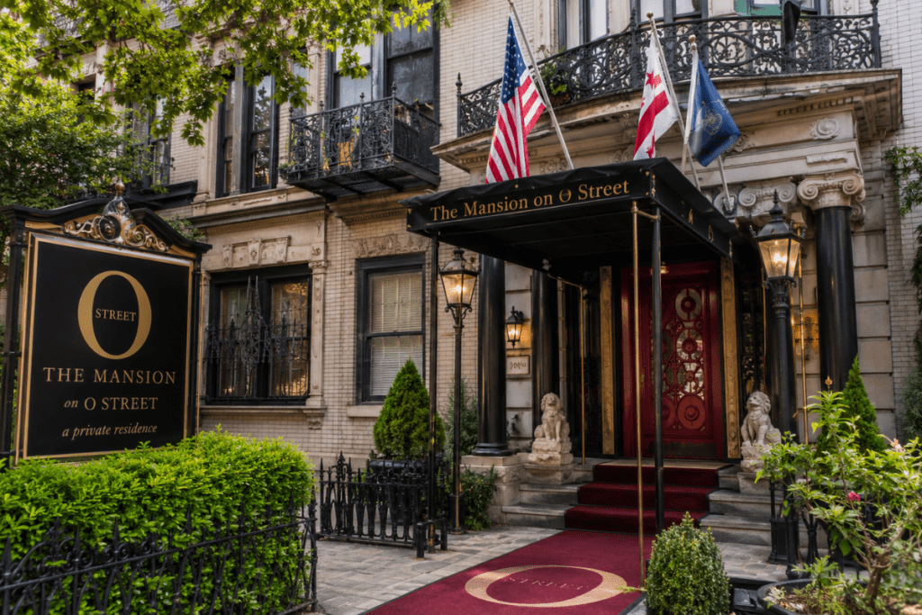 The Mansion on O Street in Washington DC with a historic entrance, elegant red door, flags, and classic city architecture.